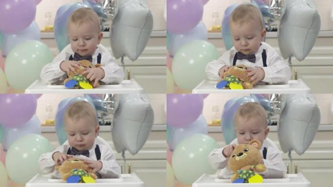 快乐的小男孩在慢动作的生日聚会上拿着礼物玩具，一岁的孩子在他的第一个生日聚会上对着彩色气球。