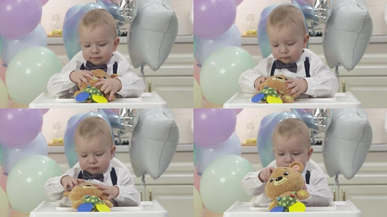 快乐的小男孩在慢动作的生日聚会上拿着礼物玩具，一岁的孩子在他的第一个生日聚会上对着彩色气球。