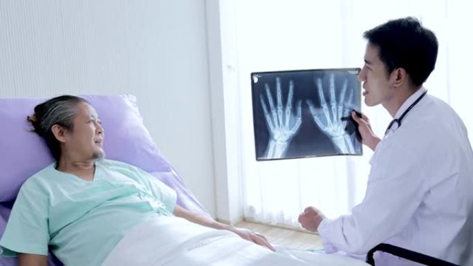 亚洲男医生手持腕骨x光片在病床上与患者交谈