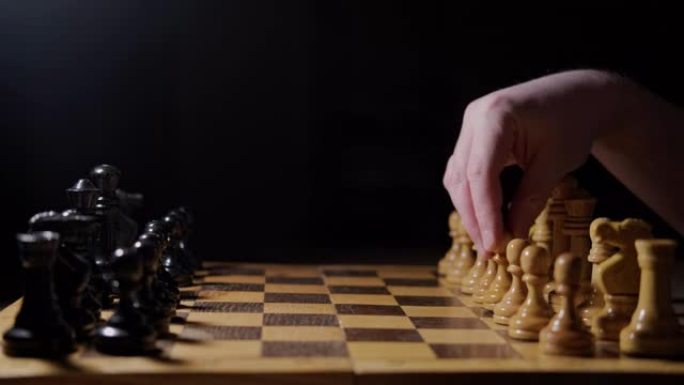 以白方兵d2-d4的移动，黑色背景开始棋后的开局。棋盘游戏中手持棋子的人。