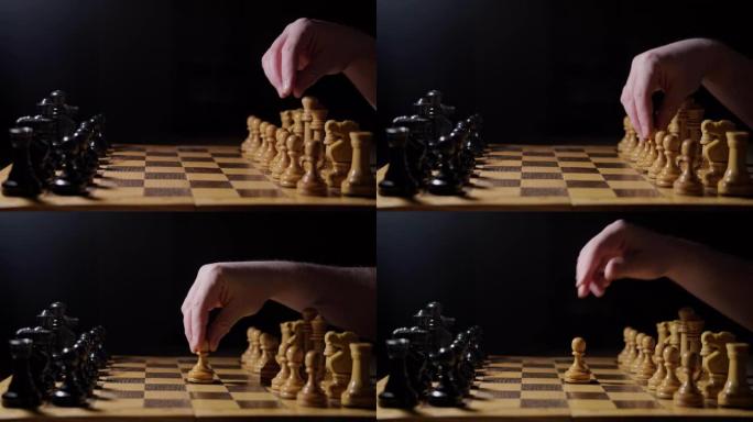 以白方兵d2-d4的移动，黑色背景开始棋后的开局。棋盘游戏中手持棋子的人。