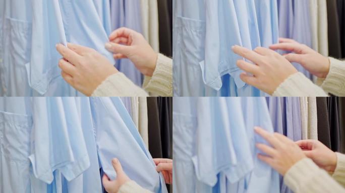 特写女性双手在衣架上整理蓝色衬衫