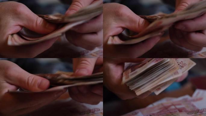 男性的手数俄罗斯的钱5000纸币的背景下旋转的一堆钱