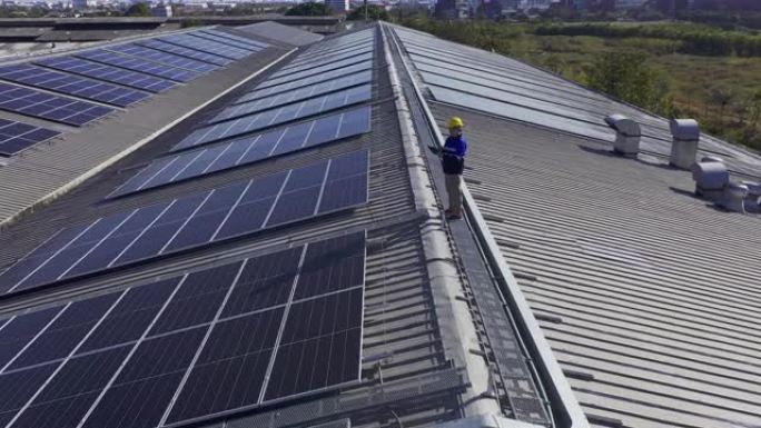 专业技术员专业工程师，配备笔记本电脑和平板电脑维护检查，在阳光下在工厂屋顶上安装太阳能屋顶面板。拿着