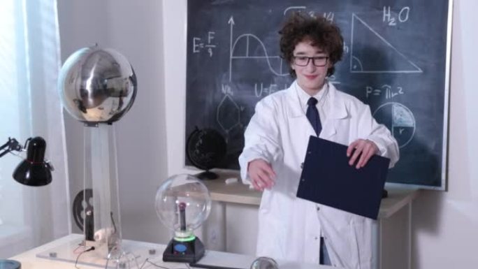 物理科学实验室: 穿着白大褂和眼镜的英俊年轻科学家做电气测试。在实验室研究放电的孩子