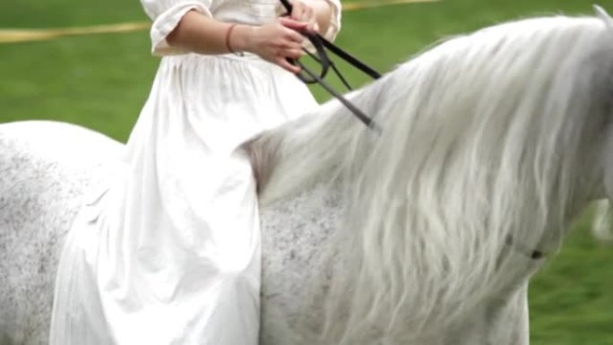 年轻女子照顾并骑着她美丽的白马