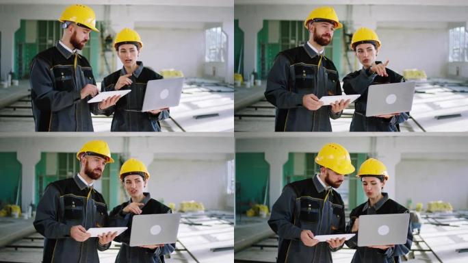 在镜头前，漂亮的女工程师和她的助手走过大空间建筑的女人拿着笔记本电脑，男人拿着数字平板电脑分析施工计