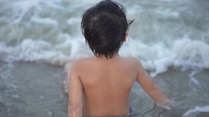 亚洲男孩在海滩上享受和玩海和沙子的慢动作镜头