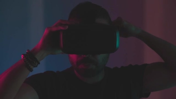 年轻人脱下VR眼镜耳机与彩色霓虹灯虚拟现实互动，未来技术，微笑g excited.edu阳离子视频游
