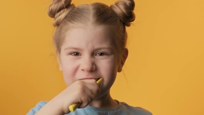 黄色背景下的女孩刷牙。儿童日常保健程序。