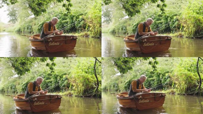 成熟的人从河上的木船钓鱼和使用智能手机