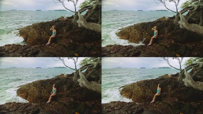 在暴风雨的早晨，多云的海中，一名女子在礁石上冥想，放松。女性的概念，性阴道健康，女性化，自由，新鲜