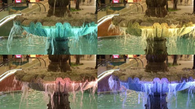 喷泉里的水往下流。水柱被涂上不同的颜色。喷泉照明。霓虹灯