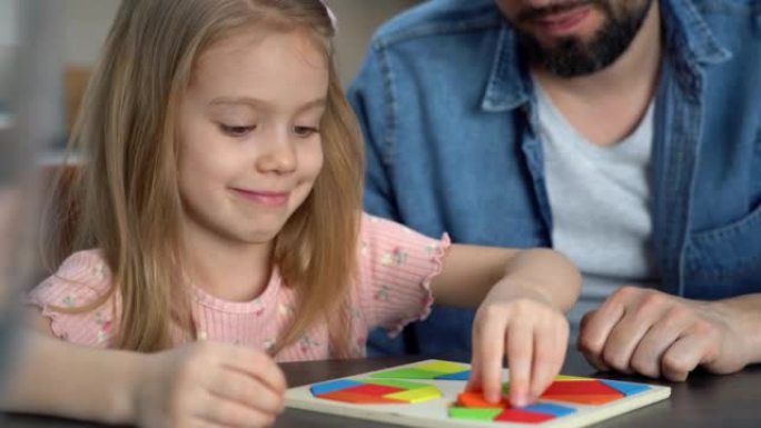 小女孩放七巧板拼图。儿童收集木制拼图。教育理念