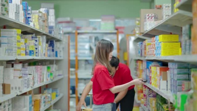 一家现代医药超市的工作人员正在帮助检查库存并对货架上的产品进行分类。