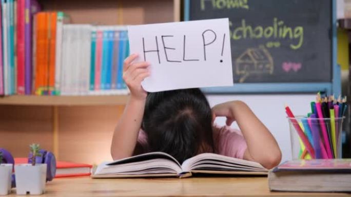 亚洲小女孩感到悲伤和疲倦，坐在桌子旁，拿着许多书，拿着文字帮助的纸。学习困难。家庭教育。
