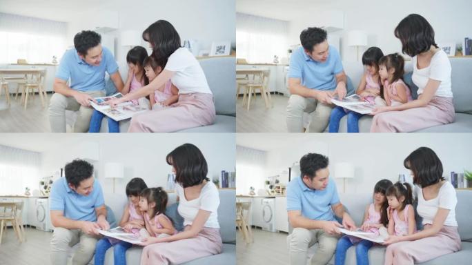 亚洲家庭看旧相册上的照片回忆过去。年轻美丽的夫妇坐在一起，带着小女儿翻动相册的页面，享受记忆的关系记