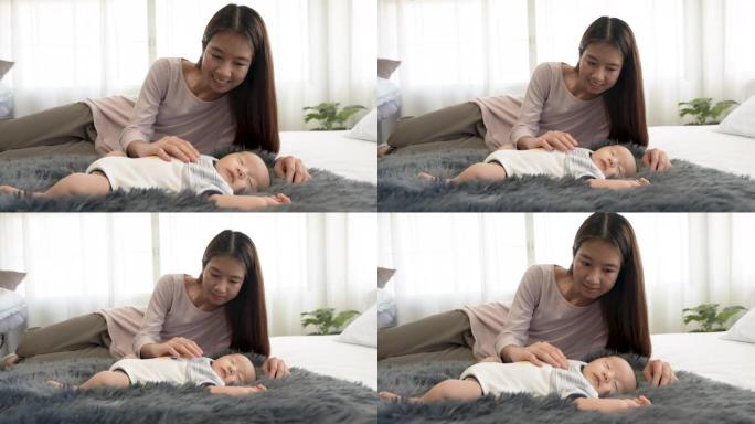 4k，一个新生儿，2个月大的亚洲婴儿正在地毯上睡觉。他妈妈哄他温暖地睡在你身边