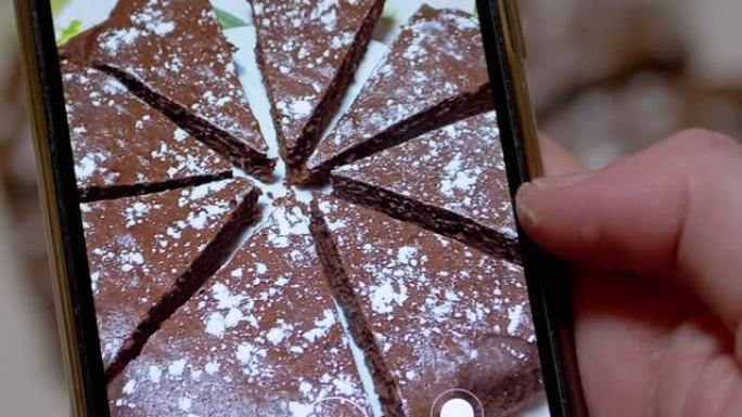 女性手在智能手机上拍摄厨房巧克力派的视频。缩放