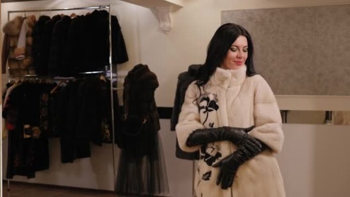 服装店里一个穿着新貂皮白皮大衣的幸福女人的肖像。