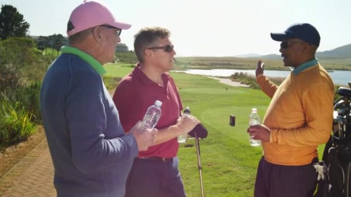 男性高尔夫球手在阳光明媚的高尔夫球场喝水和聊天