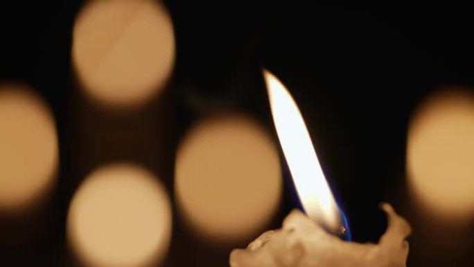 蜡烛式蜡烛在黑色背景下在黑暗中闪烁，烛光黑景效果模糊。纪念、哀悼或庆祝的背景或插图。教堂中的火焰蜡烛