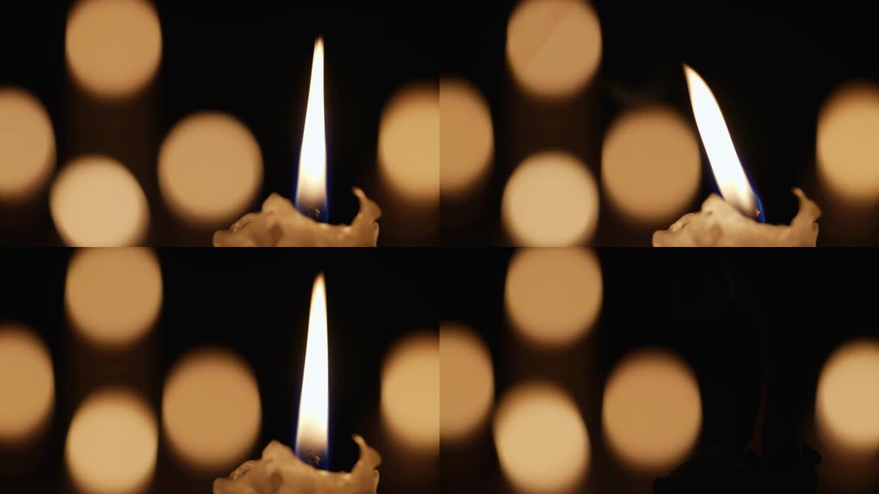 蜡烛式蜡烛在黑色背景下在黑暗中闪烁，烛光黑景效果模糊。纪念、哀悼或庆祝的背景或插图。教堂中的火焰蜡烛