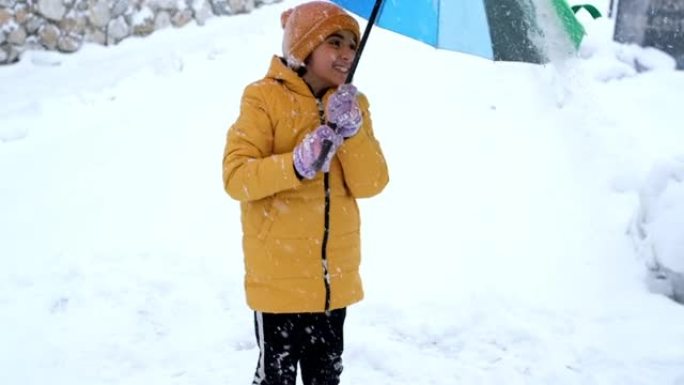 彩虹色雨伞下雪时，小女孩感到幸福