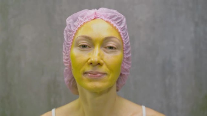 年轻漂亮女人脸上的皮肤护理程序。美容院，面部脱皮黄金海藻酸盐面膜，视黄醇处理，果酸