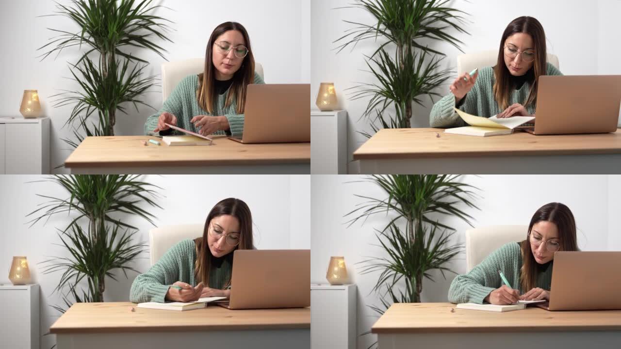 年轻的企业家女性，戴眼镜在笔记本电脑上工作，在舒适的办公室里在笔记本上写笔记