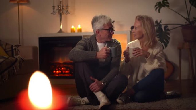 快乐的高级夫妇在壁炉旁一起放松，在家喝咖啡