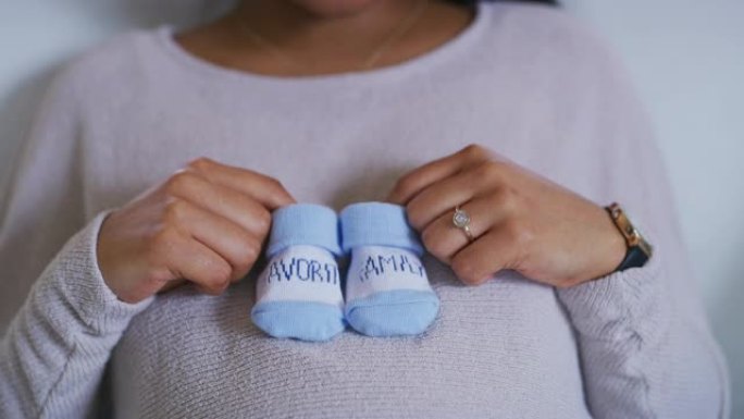 一名孕妇拿着蓝色婴儿袜的4k视频片段