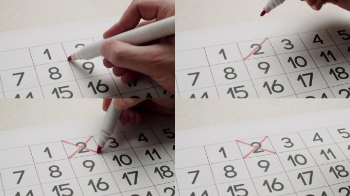 男人的手用红笔在纸质日历上写下第二天。