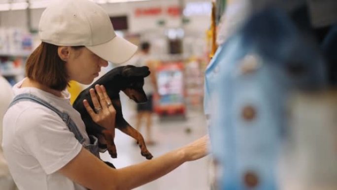 年轻女子手里拿着小狗在超市购物。