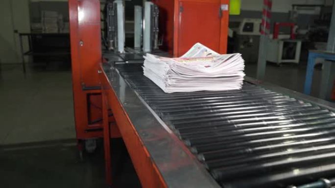 报纸成一大堆，沿着传送带移动。印刷的房子。纸质版移动时，会堆积成一大堆。媒体，文章，标题，每日新闻，