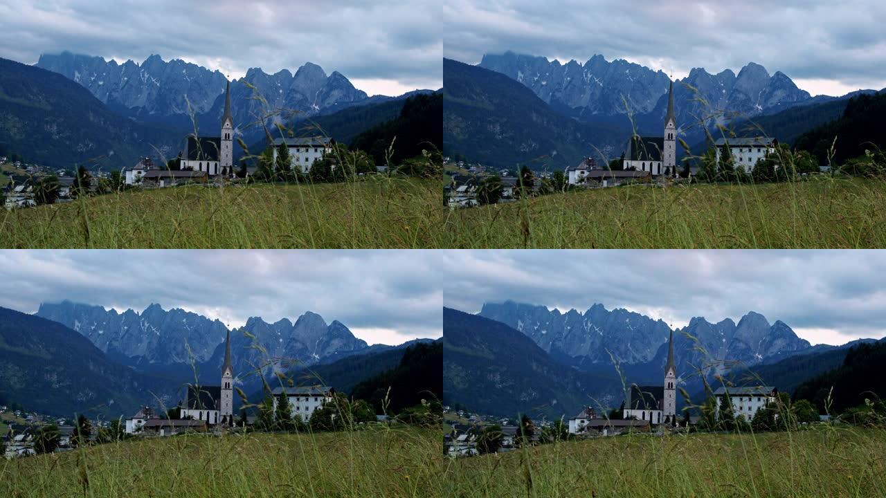 教堂和草地在戈索，奥地利，阿尔卑斯山。背景中傍晚的山脊