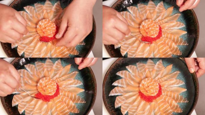食物电镀-厨师用茶匙在圆形盘子上的鲑鱼玫瑰周围添加红色鱼子酱