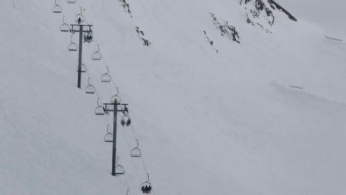 滑雪者从陡峭的斜坡上下来，而其他在升降椅上的滑雪者则在斜坡开始的高原上领先