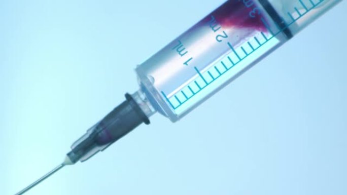 注射器蓝色背景下注射液体的特写。用药药物针头注射器流感疫苗