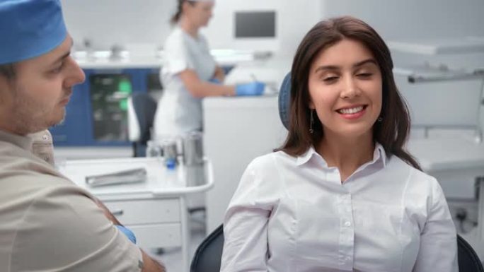 可爱的女病人在牙科手术室的口腔科医务人员中摆姿势