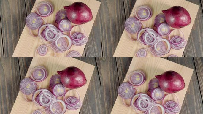 相机在木桌上的一块光板上向上移动去皮的紫色洋葱和切成薄片的洋葱。制作新鲜夏季沙拉的概念。顶视图。跟着