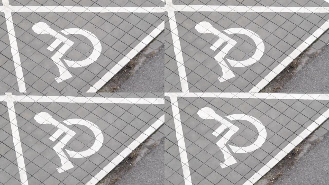 残疾人停车位为空，地上有残疾人轮椅符号。停车位为残疾人指示灯亮在路面上，在停车场室外区域，近距离，无