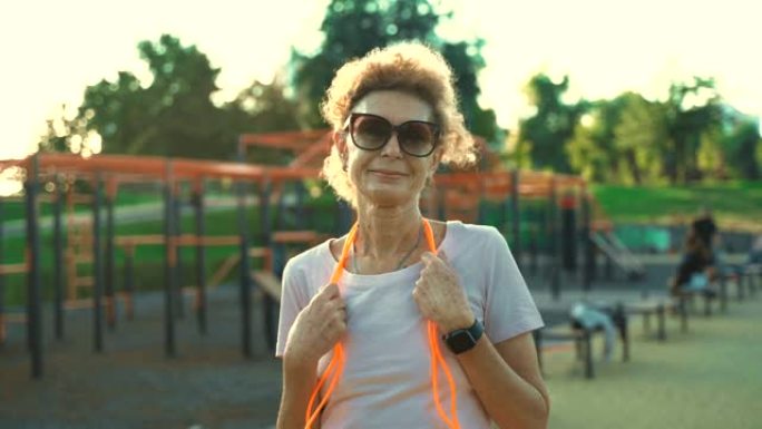 老年妇女在户外用跳绳锻炼。概念成熟时积极的生活方式和医疗保健。退休后的健康生活方式。老年女性用跳绳做