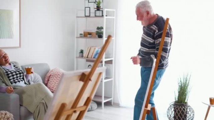 快乐的老人跳舞，享受音乐的乐趣，享受在家画布上绘画后的空闲时间