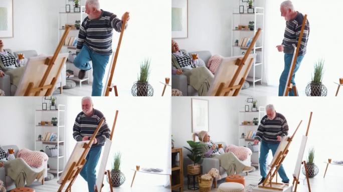 快乐的老人跳舞，享受音乐的乐趣，享受在家画布上绘画后的空闲时间