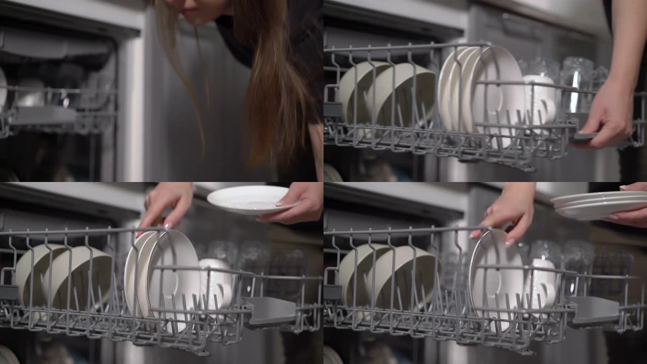 厨房里的年轻女子打开洗碗机，装载并取出盘子