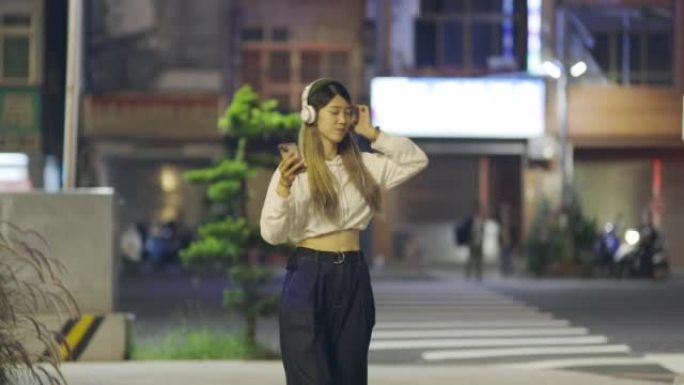 一个在街上享受音乐的亚洲女人