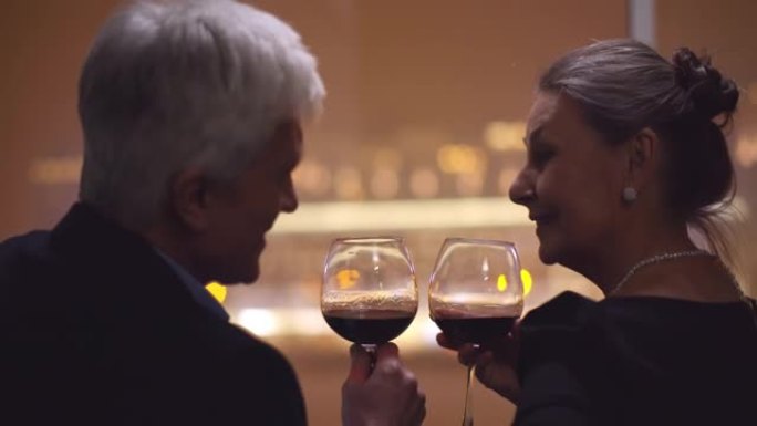 老年夫妇在家喝红酒享受景观酒店全景窗口的背影