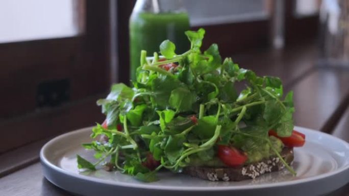 新鲜健康的素食鳄梨吐司配微绿色沙拉和樱桃番茄，在餐厅享用早餐。富含纤维维生素的健康饮食有助于延长寿命