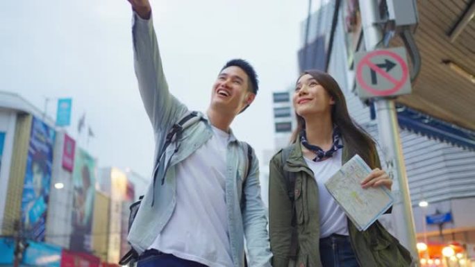 亚洲活跃的年轻夫妇晚上在城市旅行度蜜月。迷人的新婚姻男女背包客游客走在街上享受花时间在情人节假期约会